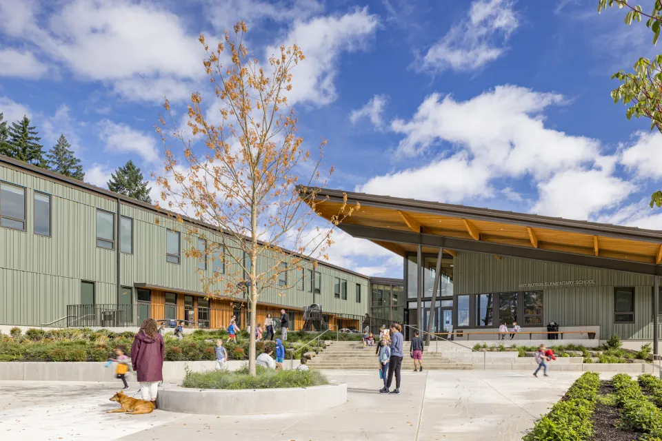 Green u-shaped school building with slanted roof and courtyard in the middle